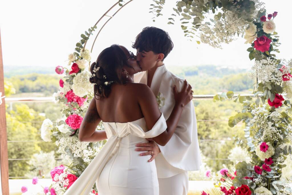 Boda en Ibiza: pareja besándose bajo un arco floral organizado por una wedding planner