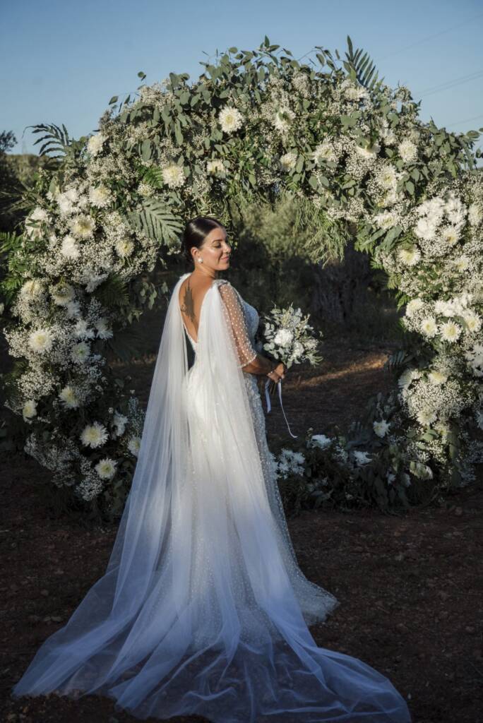 Novia bajo un arco floral blanco en Ibiza