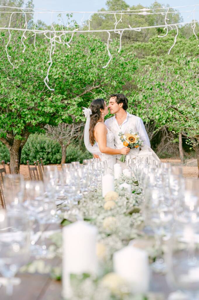 Novios besándose junto a la mesa del banquete en Ibiza